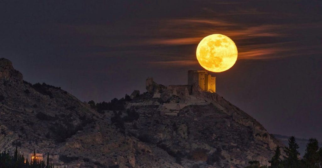 Majestic full moon rising over the historic Mula Castle in Murcia, Spain, showcasing serene night landscape.